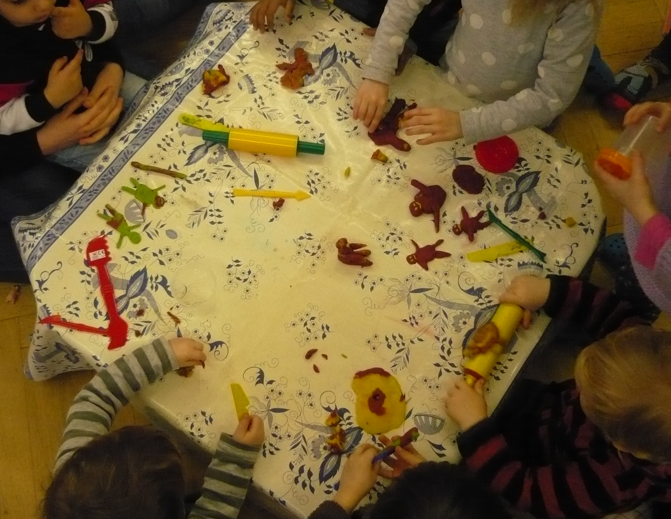 Tisch mit Kinderhänden, die wie beim 6. Schöpfungstag Menschen aus Knete formen, Foto: Anja Jäckel